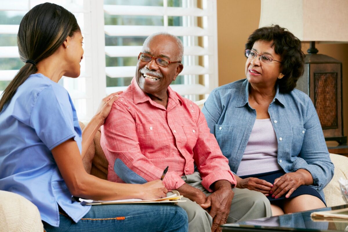 Smiling senior couple meeting with a financial advisor about hybrid long-term care insurance options.