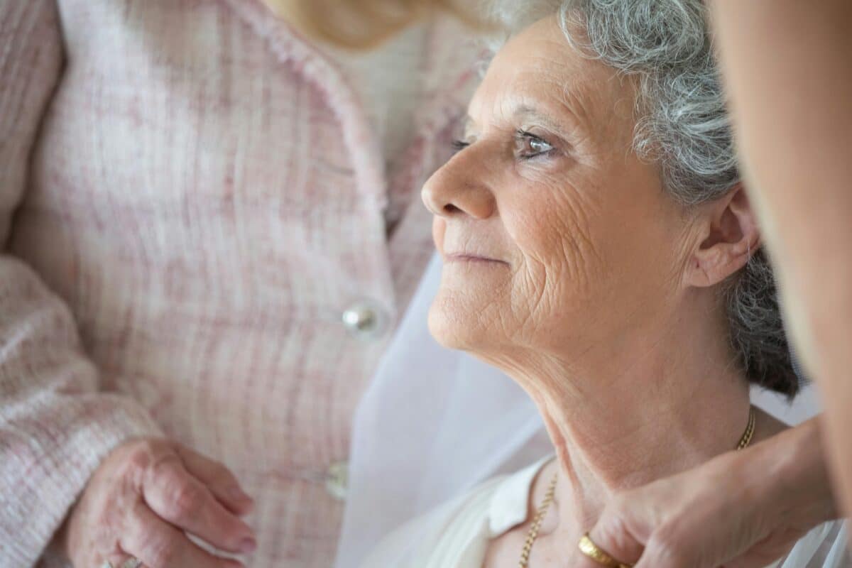 Elderly woman with caregiver and a smile on her face. Promoting Alzheimer’s prevention and brain health.