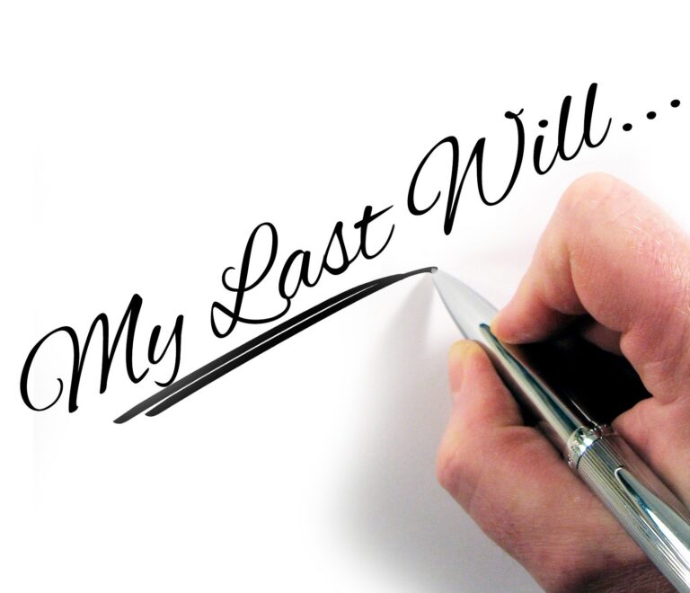 Hand holding a pen writing "My Last Will" on white paper, symbolizing will creation and estate planning.