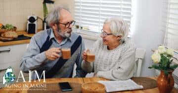 Elderly Maine couple discussing finances and future planning over coffee while preparing estate planning documents for Alzheimer's care.